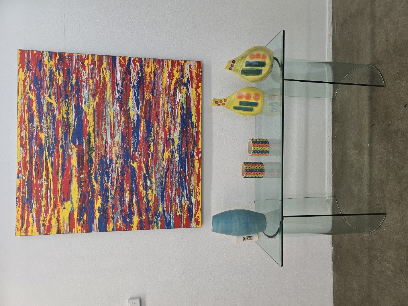 Abstract painting above ceramic vessels on a glass console